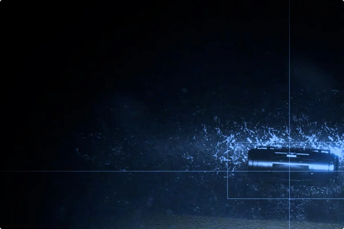Rectangular metallic object emitting blue sparks and particles surrounded by a faint rectangular target outline on a dark background.