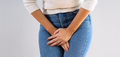 Woman standing with hands clasped in front of her body, representing bowel control treatment