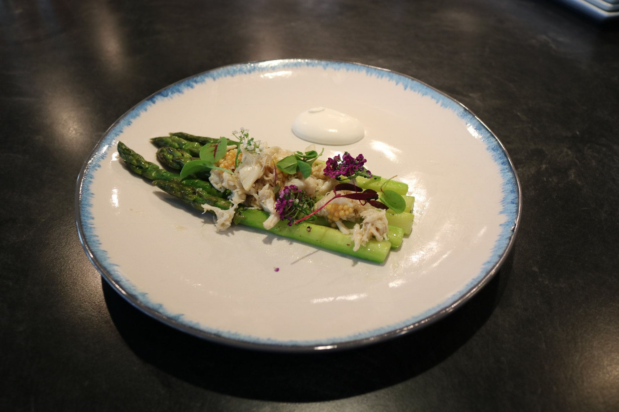 Asparagus with crab, mustard seed and blossoms on a blue-rimmed plate