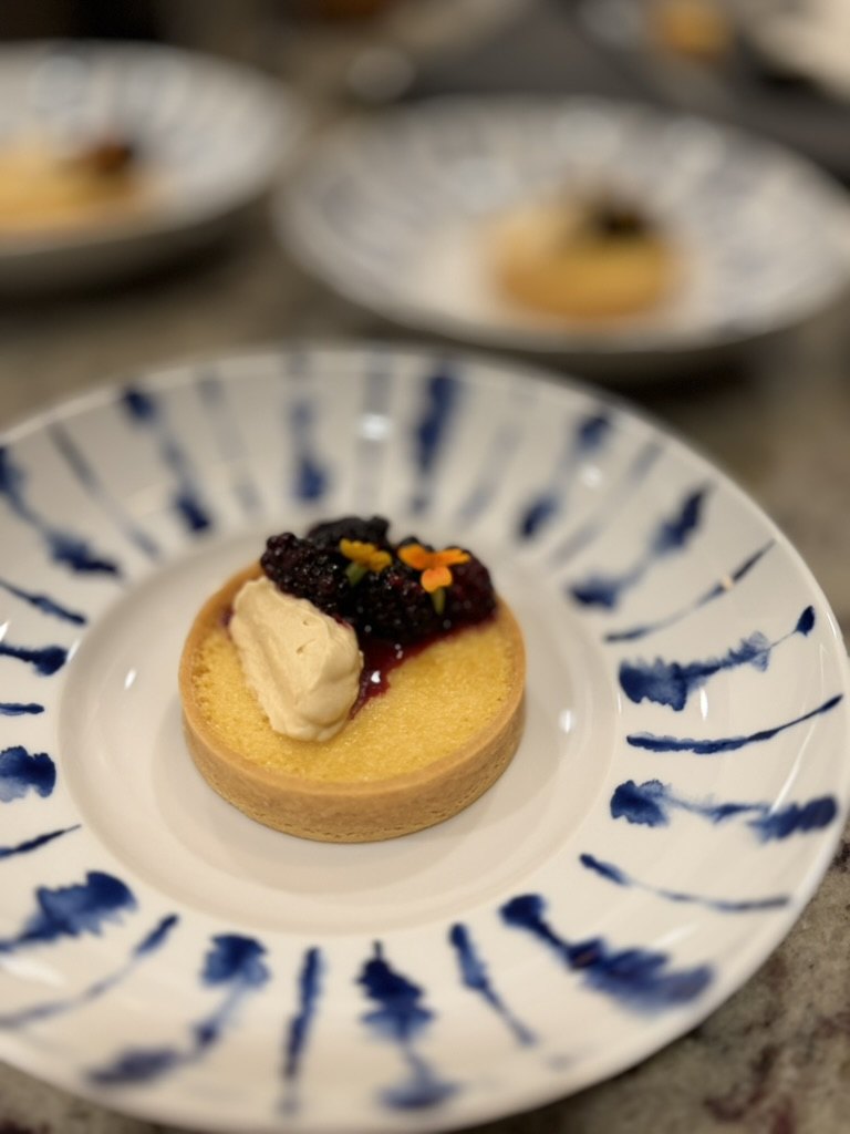 Blackberry tart with cream on a blue-striped plate