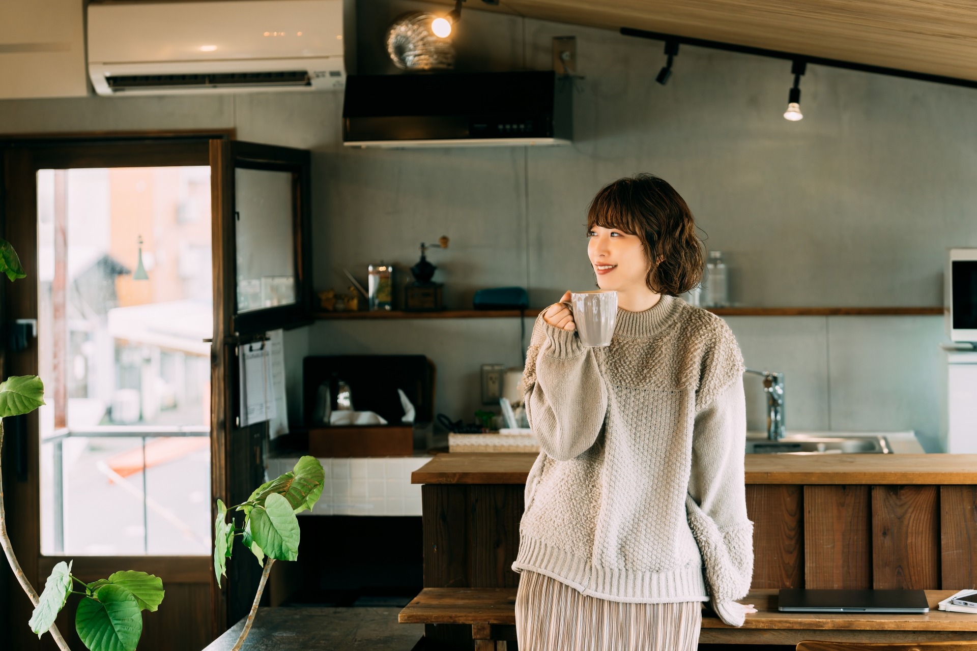 コーヒーを片手に窓の外を眺める女性