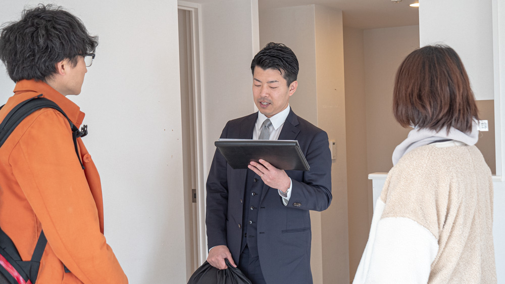 資料を使いながら内見中のお客様と話すAIME担当者