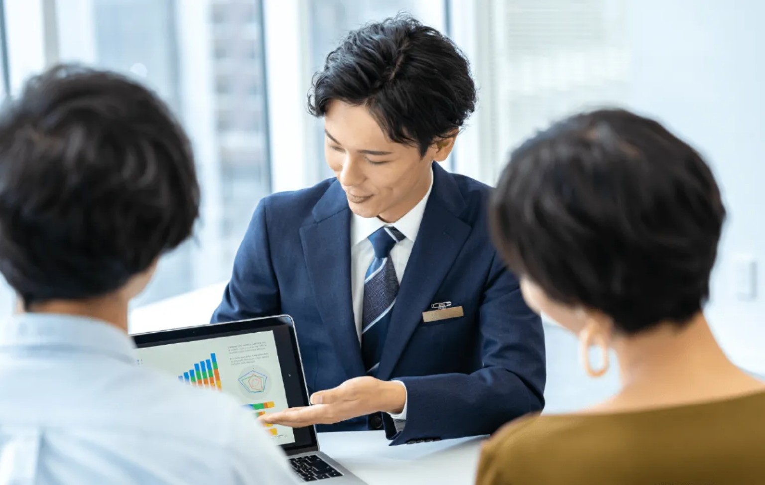 スーツ姿の営業担当者がお客様に資料を説明する商談のイメージ