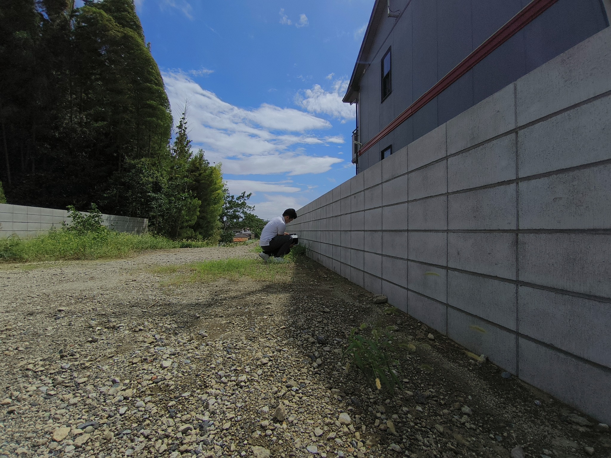 塀の足元を確認する平山