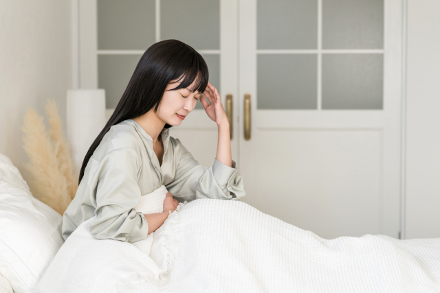 体調を気にしながらベッドで休む女性