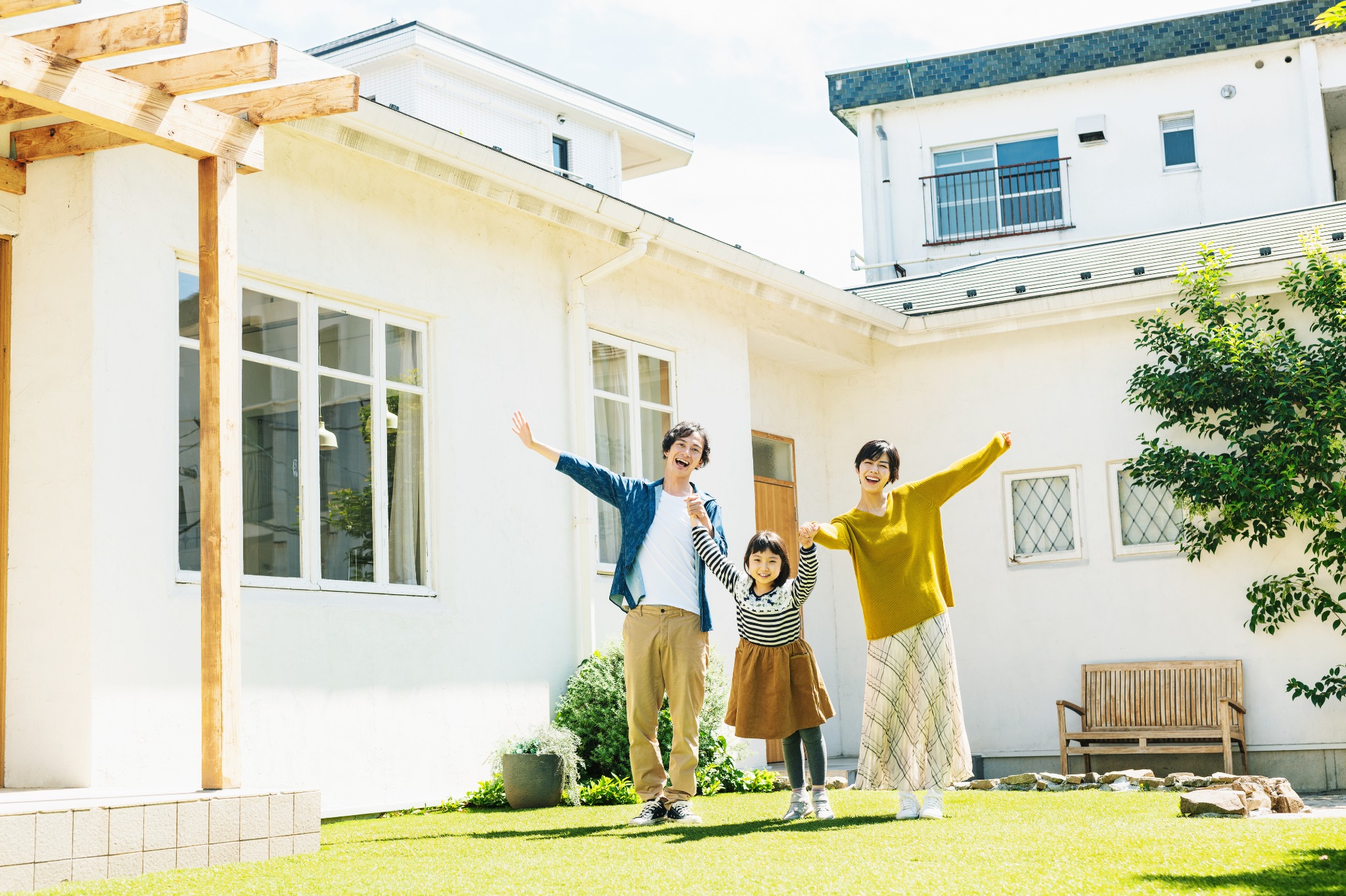 明るい庭で手をつなぎ、笑顔で過ごす家族