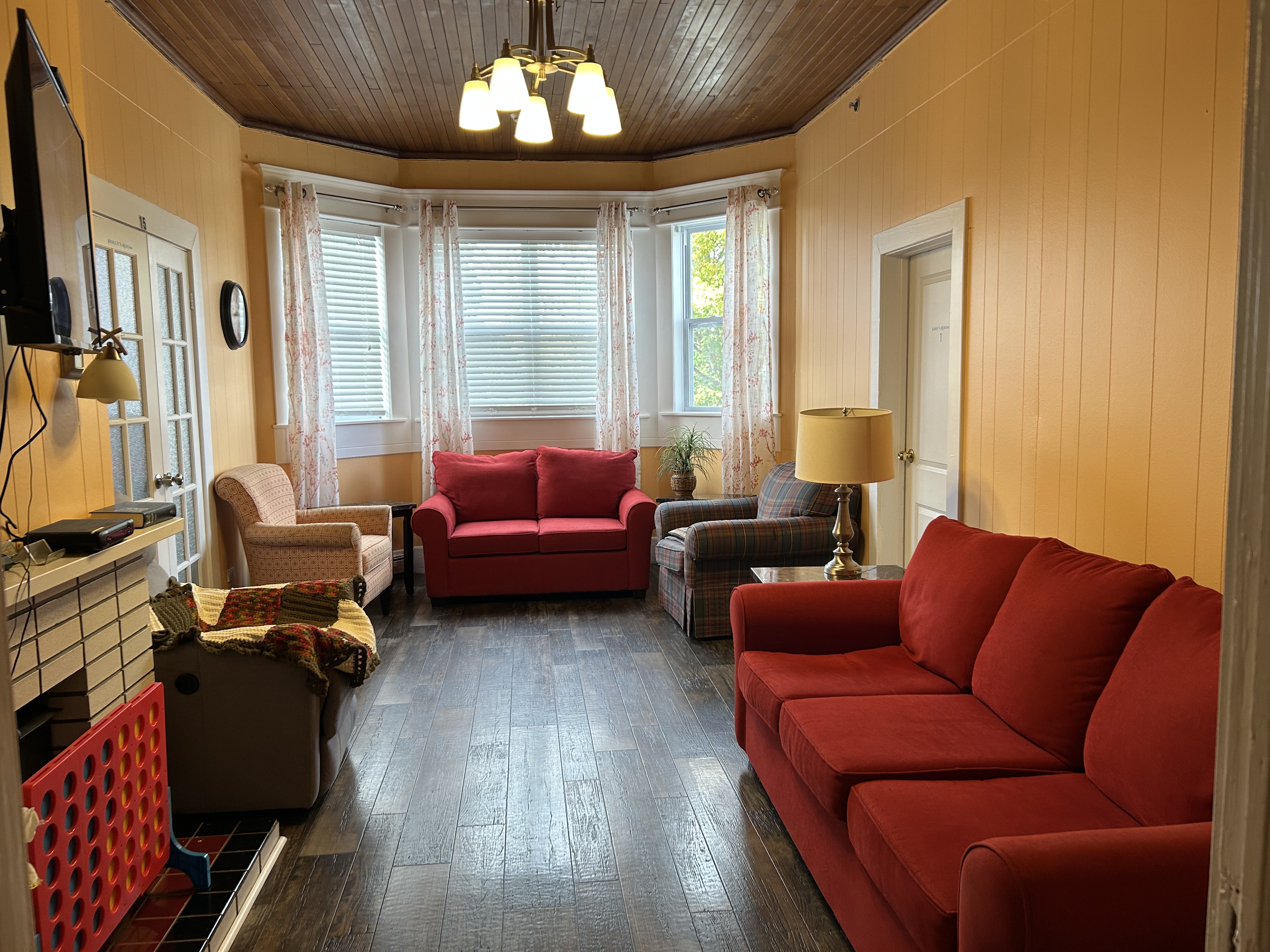A bright living room with red sofas and a wood-panelled ceiling in a Connections for Seniors home
