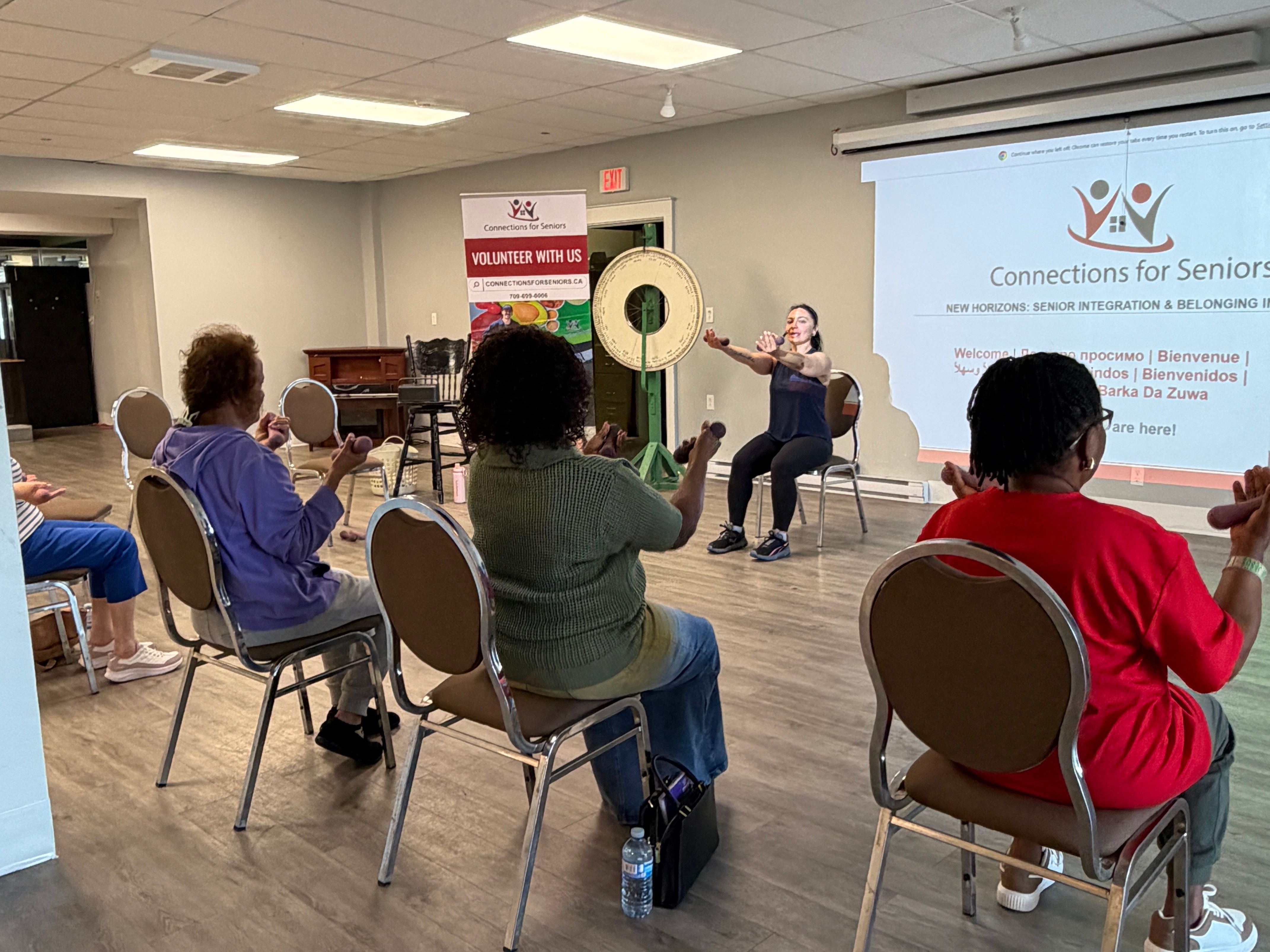 An instructor leading a seated exercise class for older adults in a community room