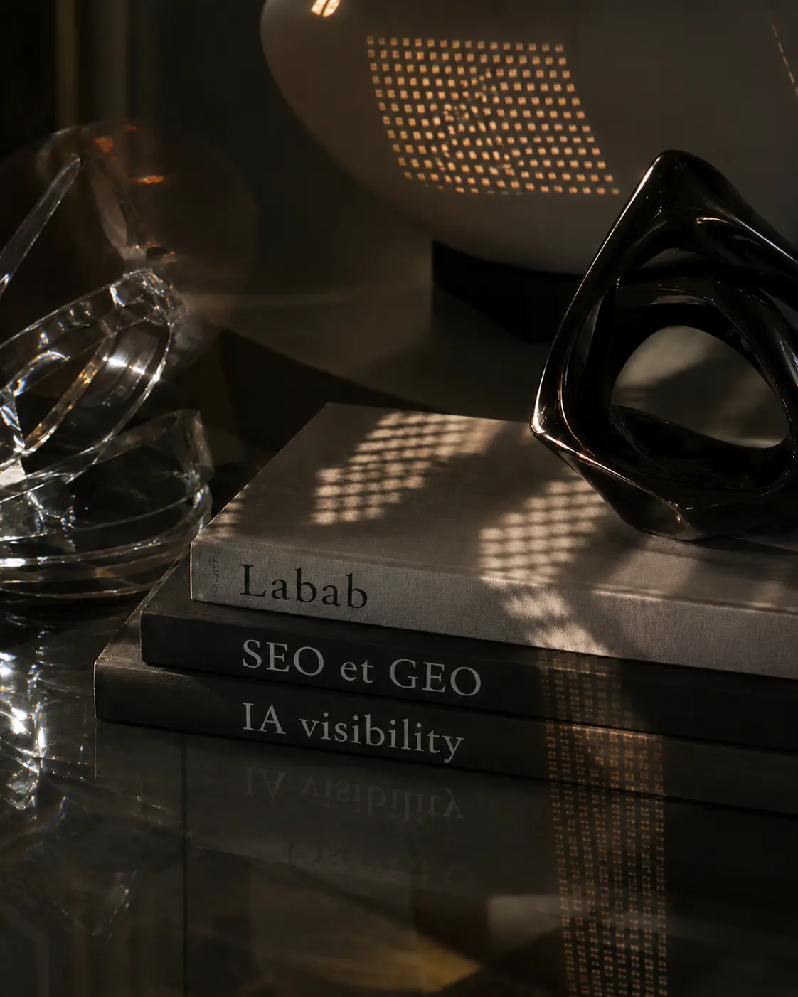 Trois livres empilés — Labab, SEO et GEO, IA visibility — supports de la formation GEO de LAB.AB