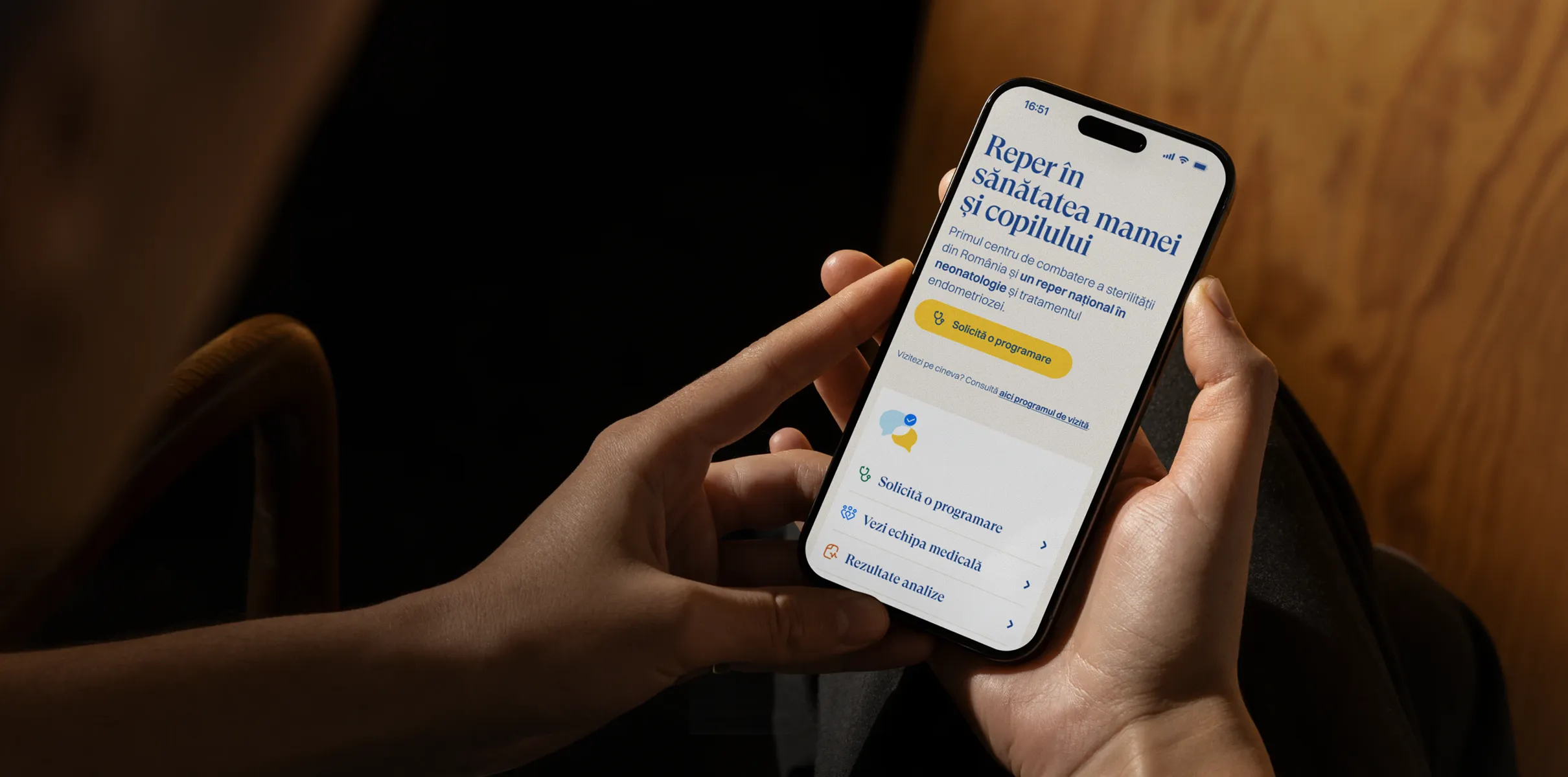 Mâini care țin un telefon cu site-ul Maternității Giulești deschis