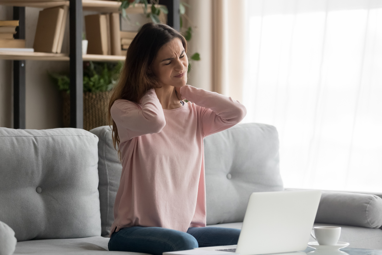 Frau mit Nackenbeschwerden im Alltag am Laptop