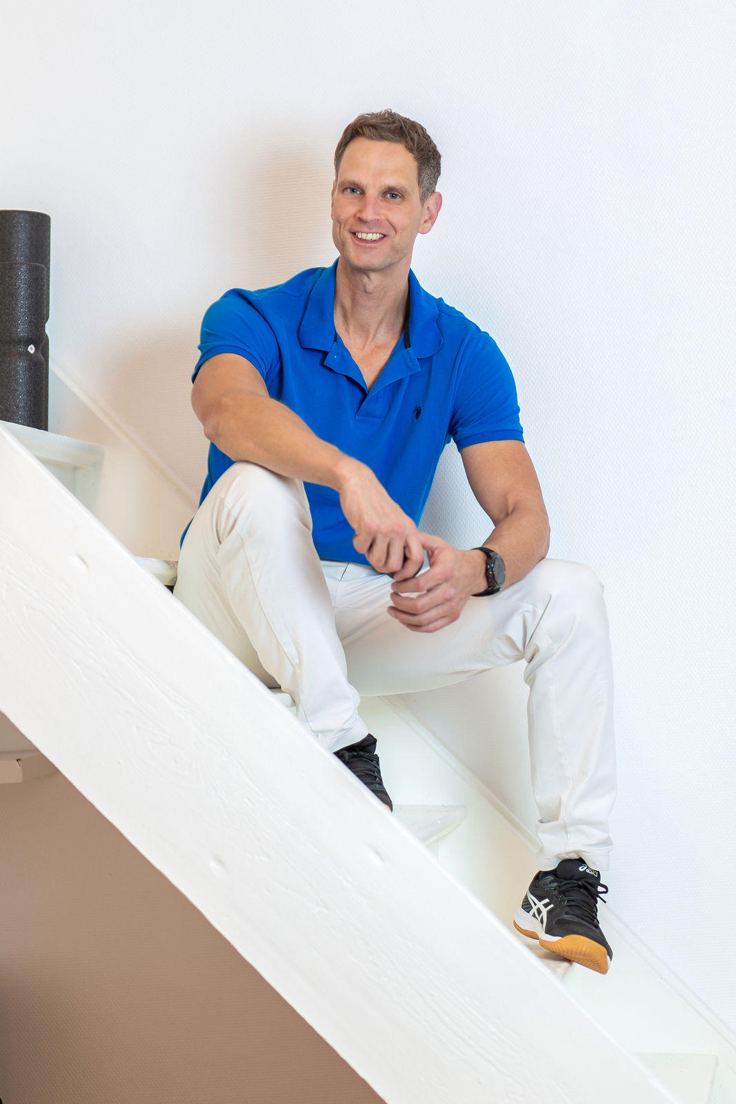 Philipp Dreisbach sitzt lächelnd auf der Treppe in seiner Praxis