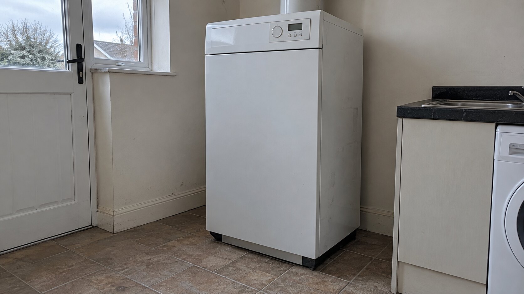 Closed floor-standing oil boiler in a domestic utility room.