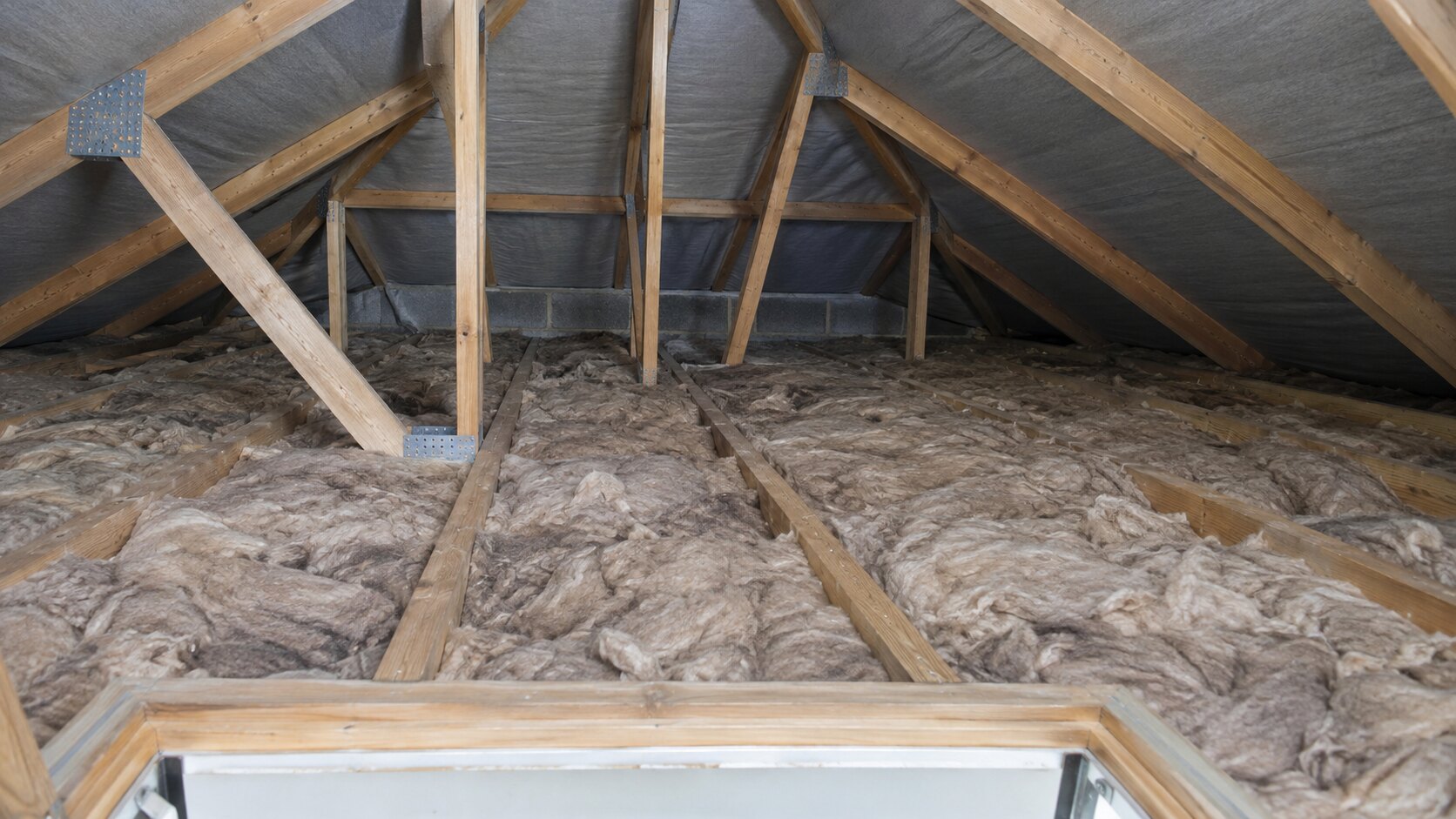 Mineral wool insulation between timber joists in a bungalow loft.