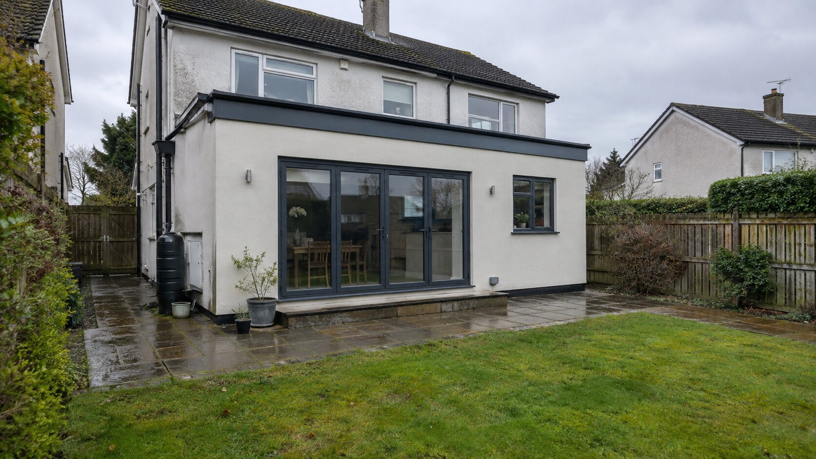 Single-storey rendered rear extension with glazed doors opening onto a patio.