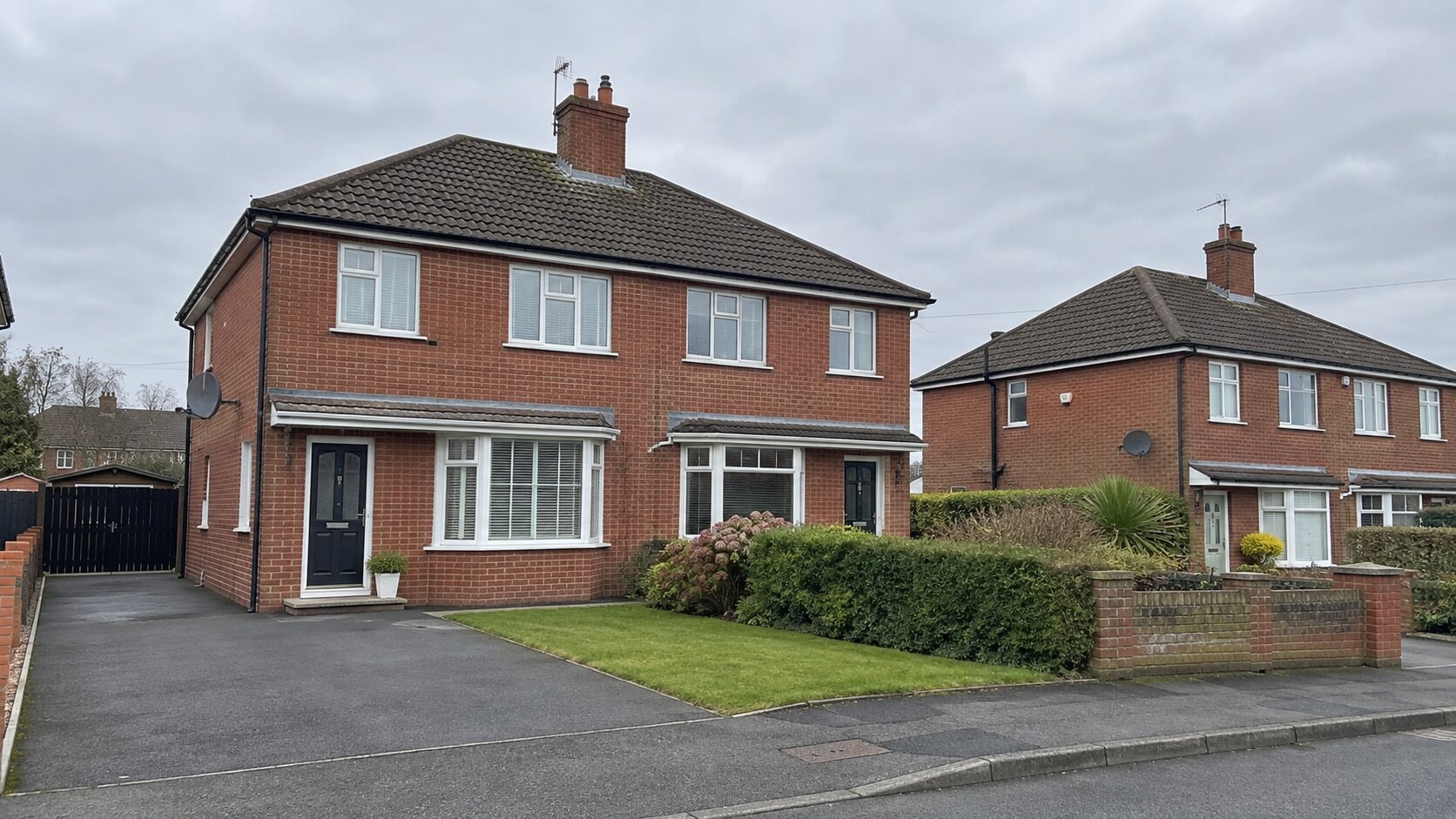 Red brick semi-detached homes with tiled roofs and small front gardens.
