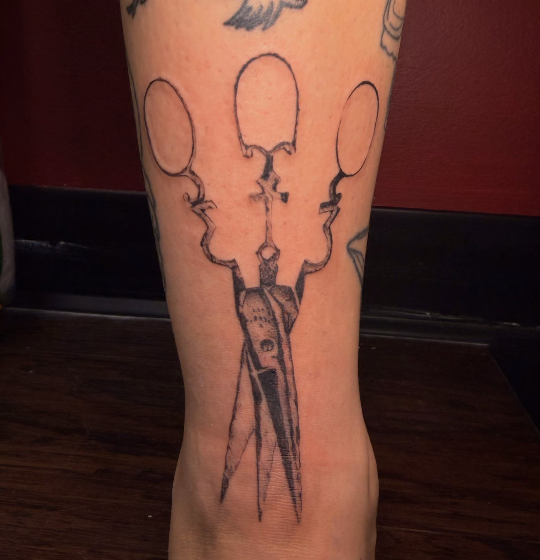 Blackwork dagger and shears leg tattoo