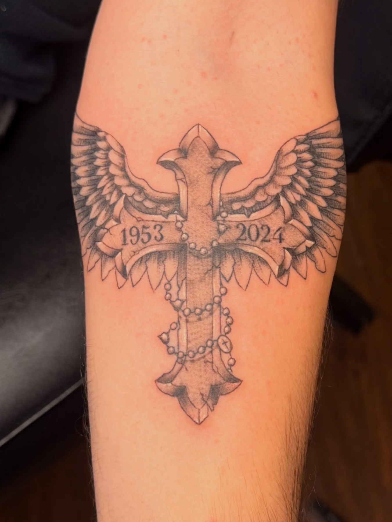 Memorial cross tattoo with wings and dates