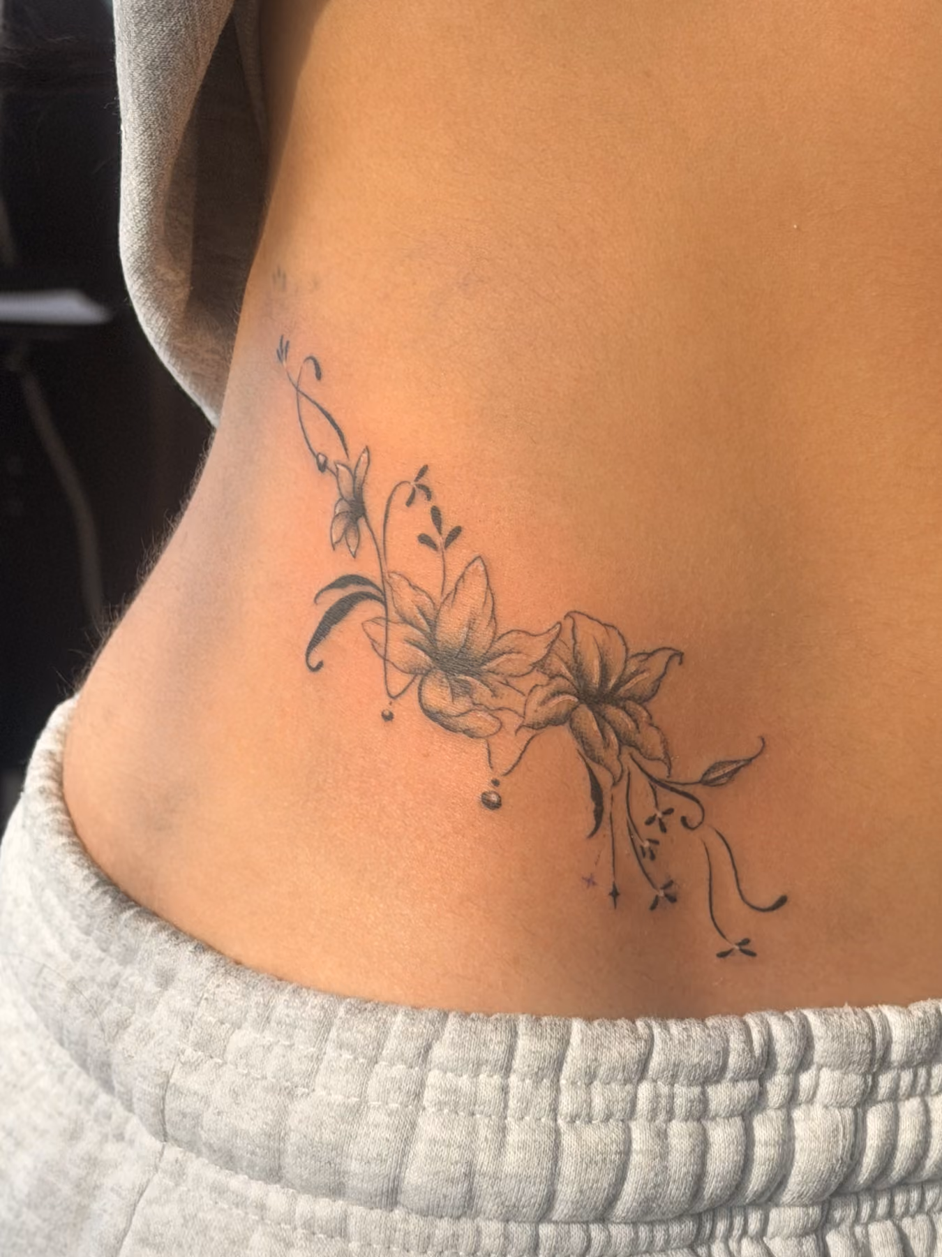 Fine line floral hip piece tattooed at Thorn & Dagger Ink