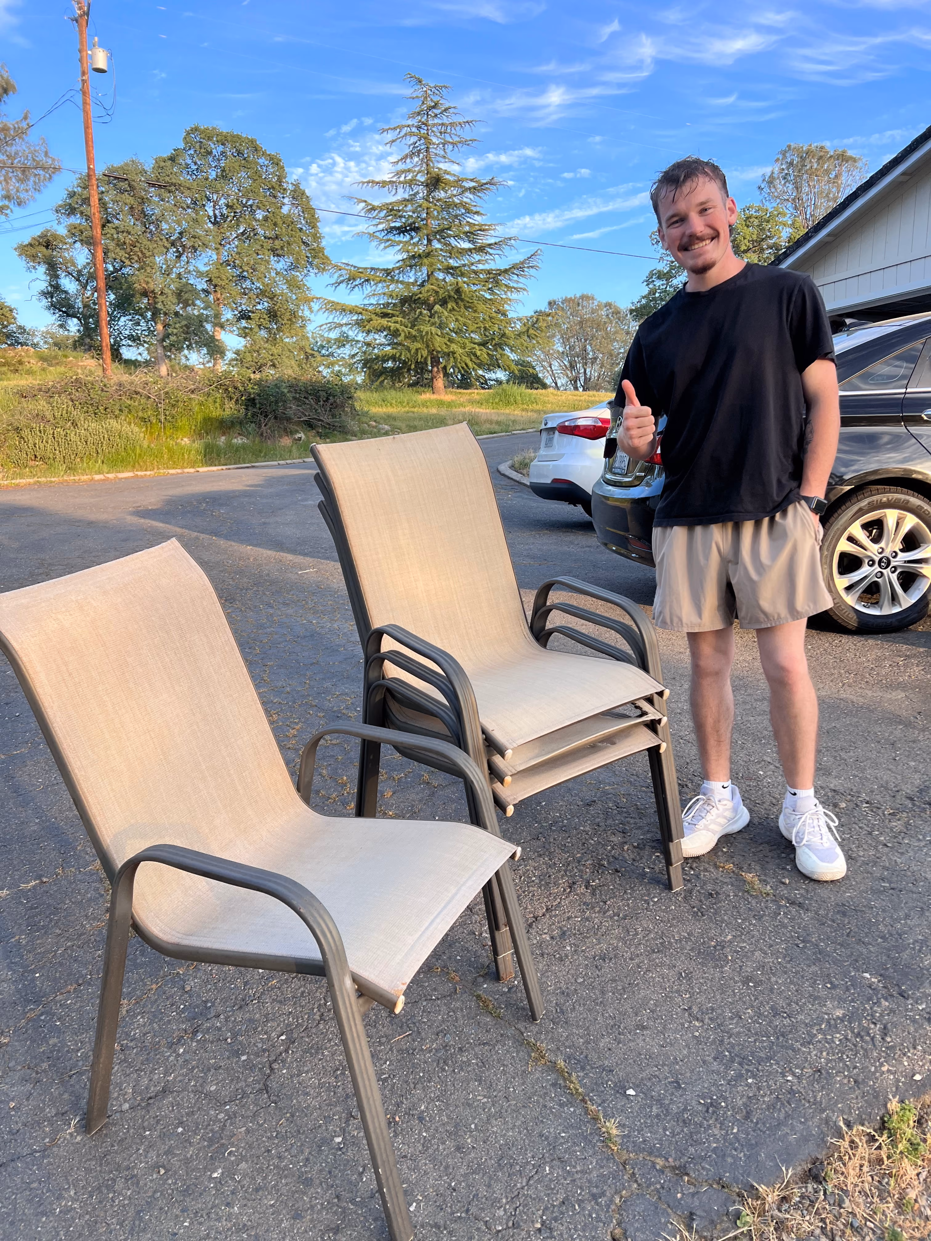 Aidan collecting three old patio chairs from a driveway
