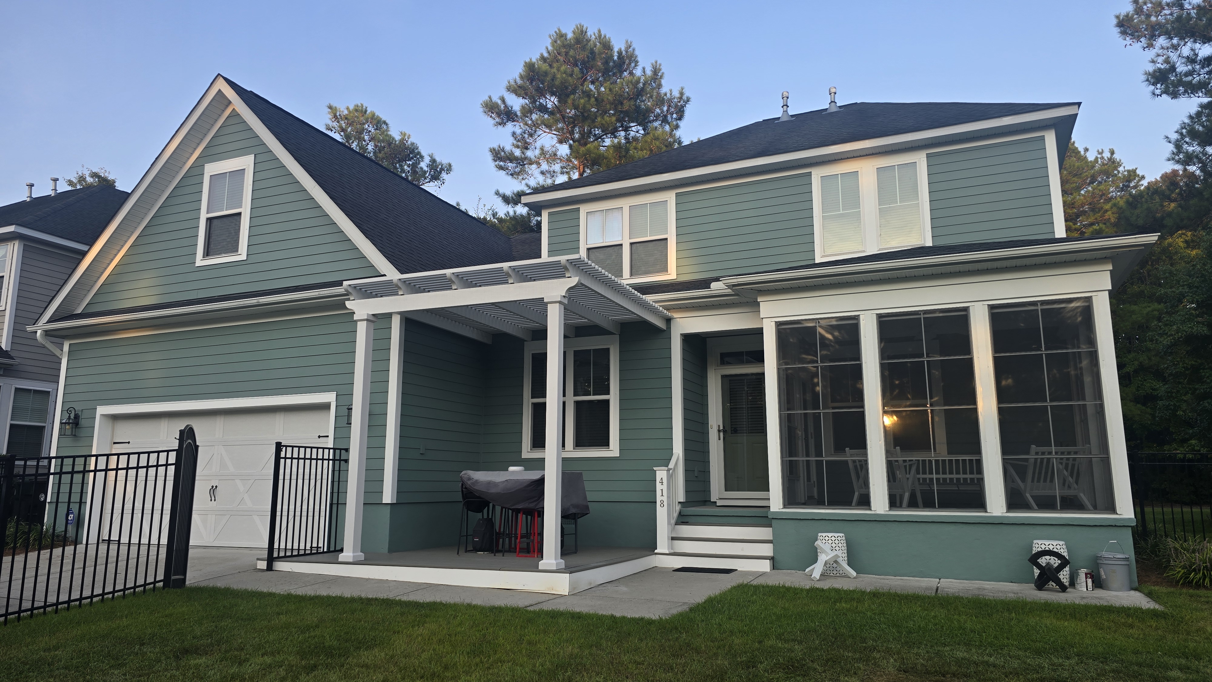 Two-story home with newly painted green siding, white trim and screened porch by PaintSmart