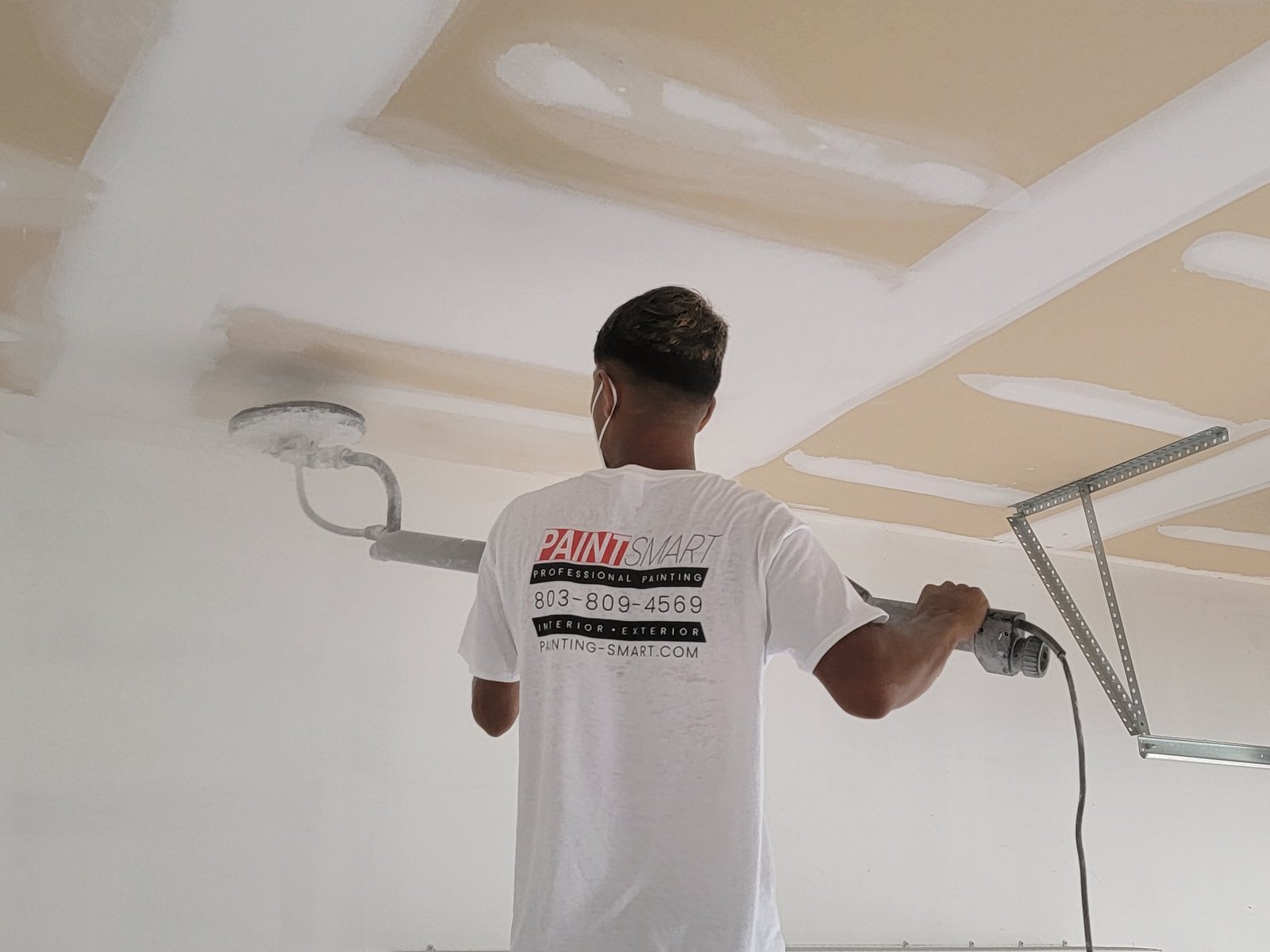 PaintSmart painter sanding a garage ceiling as part of careful surface prep