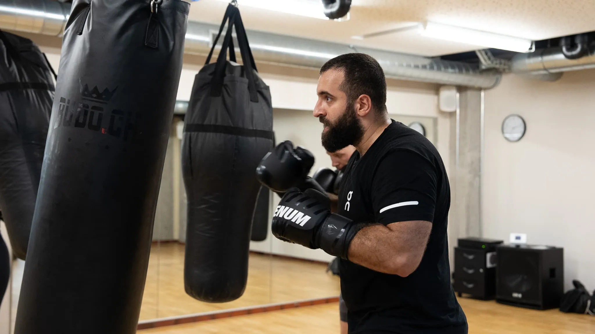 Boxer mit schwarzen Handschuhen beim Sandsacktraining im Boxclub