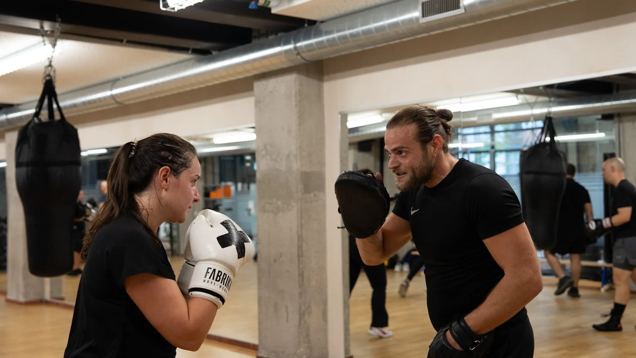 Teilnehmerin übt Pratzenarbeit mit ihrem Trainer im Gruppentraining in Dübendorf