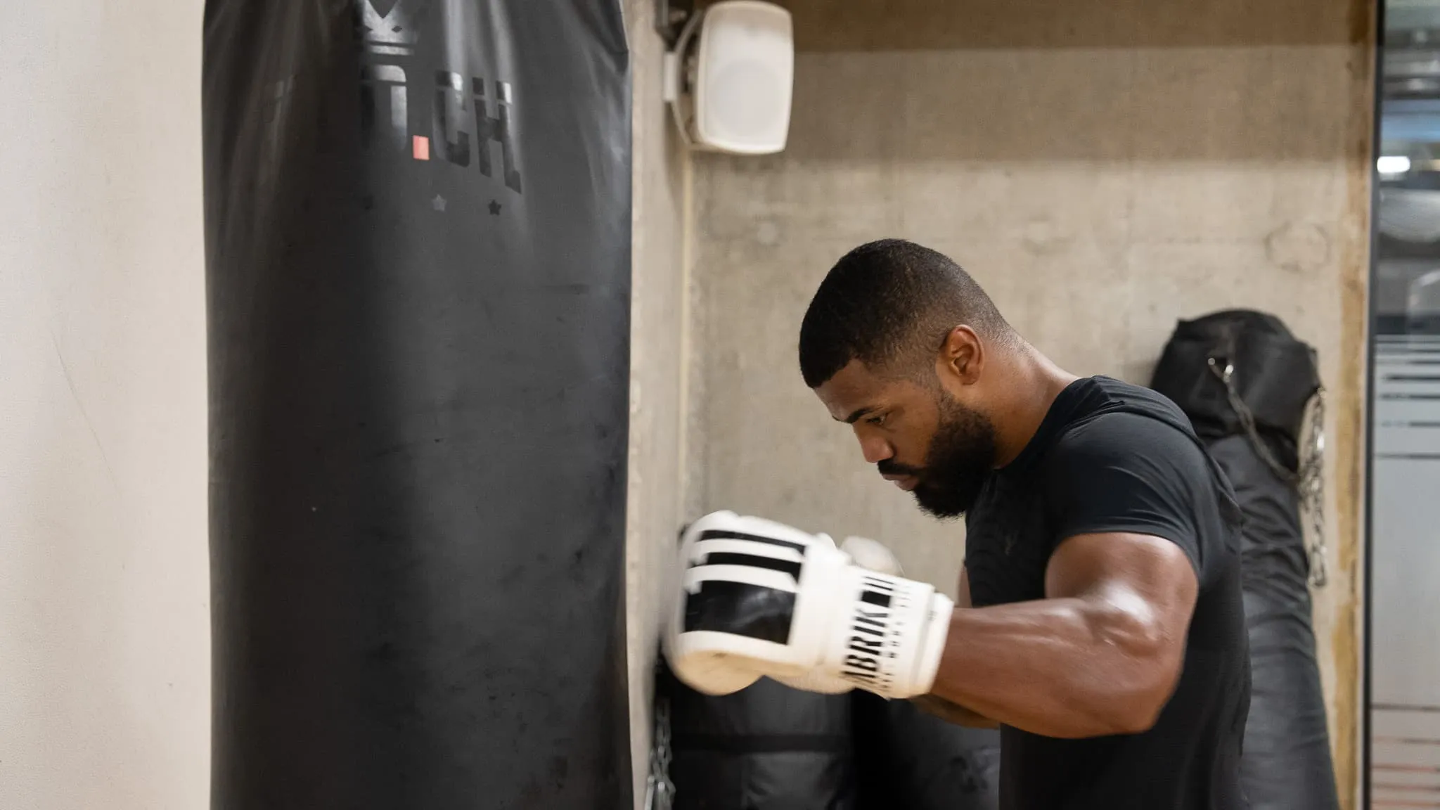 Boxer in Seitenansicht beim Schlagtraining am Sandsack im ProFight Gym