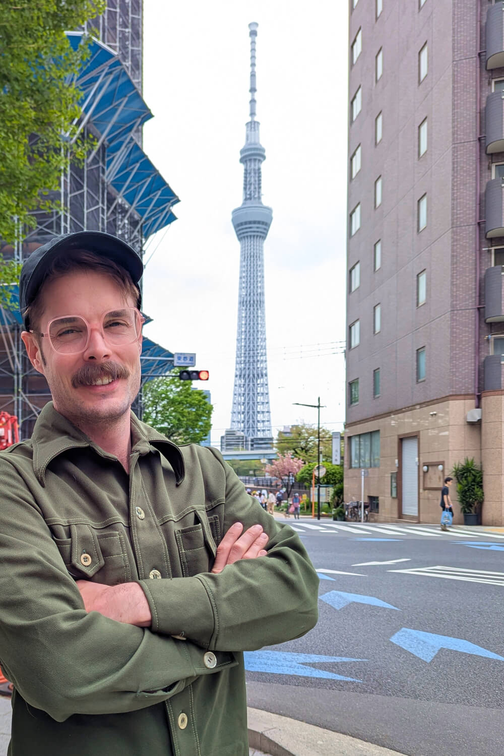 Photo of Alexander wearing a green shirt with Tokyo Tower centered in the background.