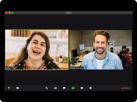 Two people on a Zoom video call, a woman smiling on the left and a man smiling on the right, both in casual office settings.
