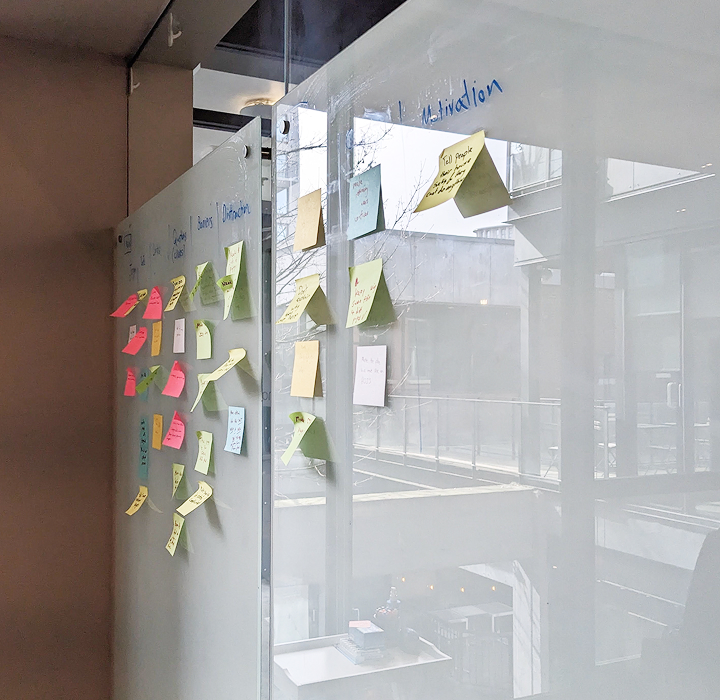 Colourful sticky notes covering a glass office partition, organized under handwritten category headers