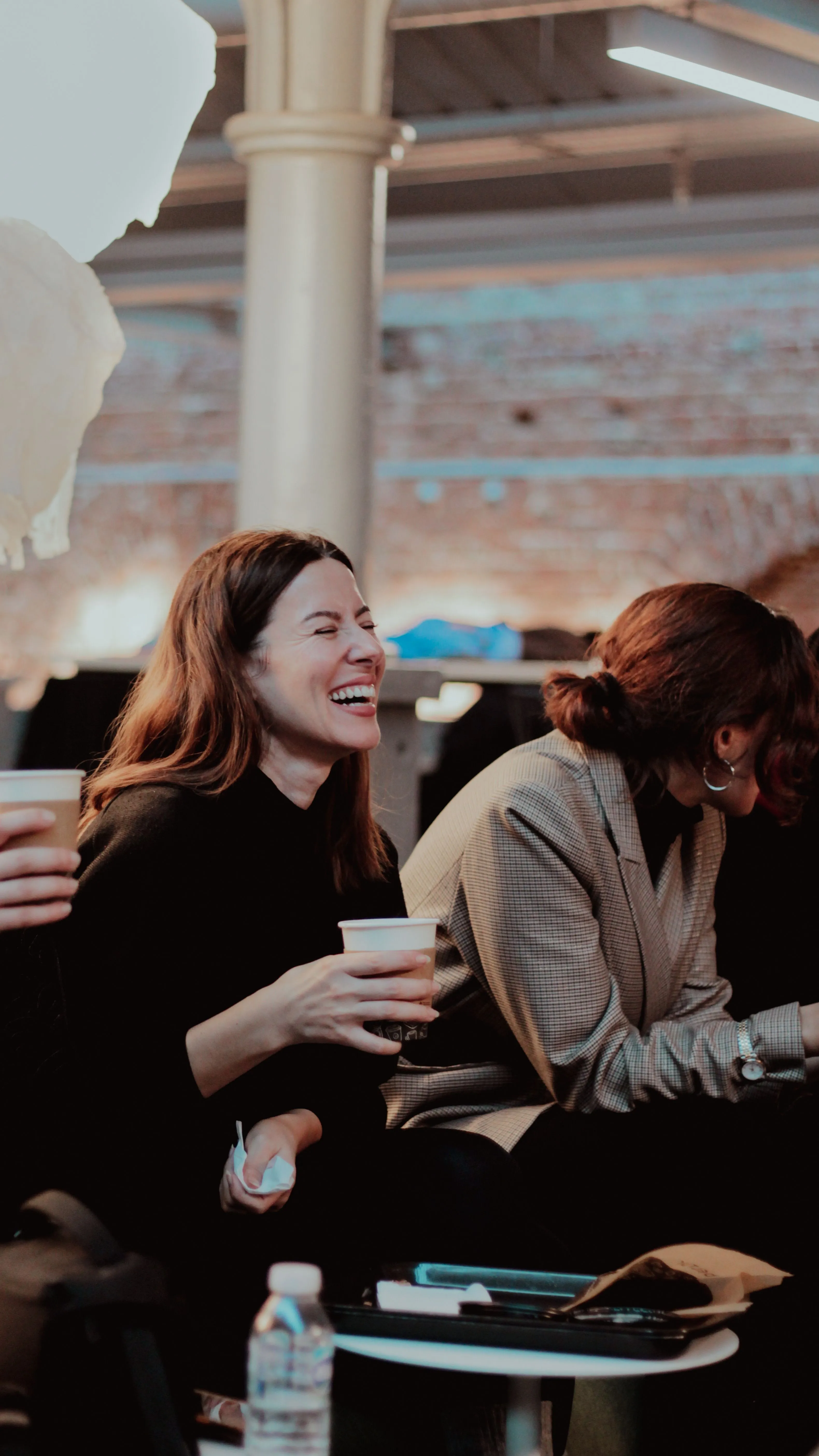 A woman laughing with friends over coffee