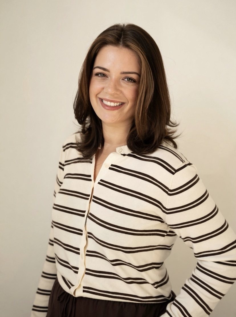 Liza LeBlanc, smiling with arms crossed, in a black cardigan over a white top