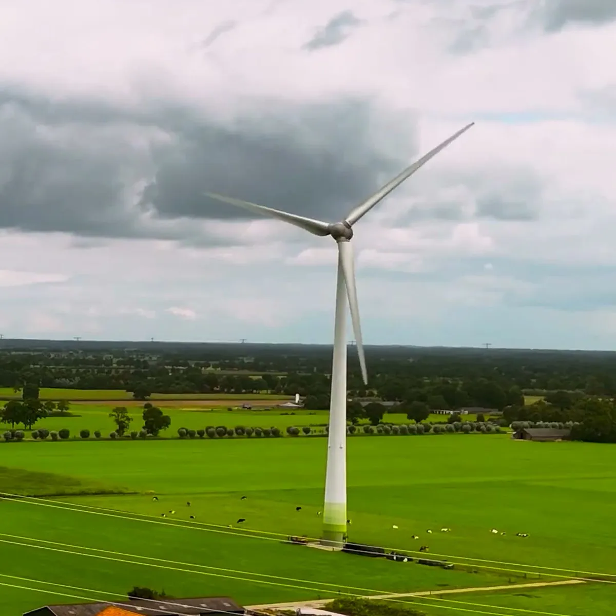 Aerial view of a wind turbine above a farmhouse and green fields