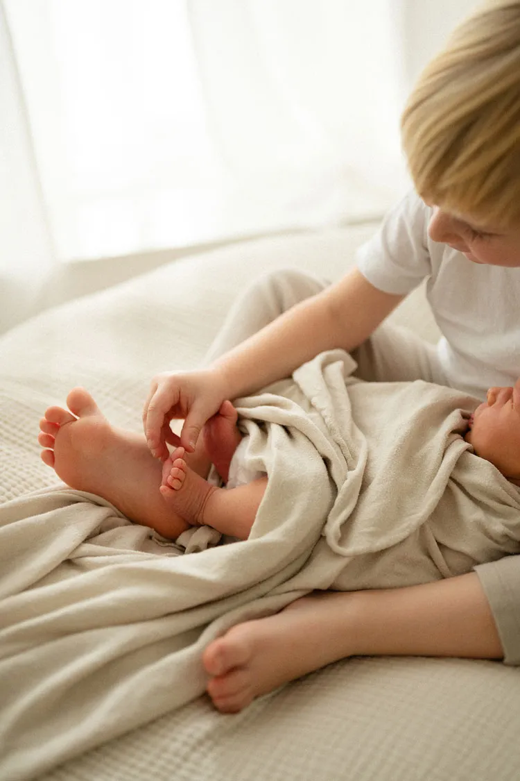 Fratello che gioca con i piedini del neonato