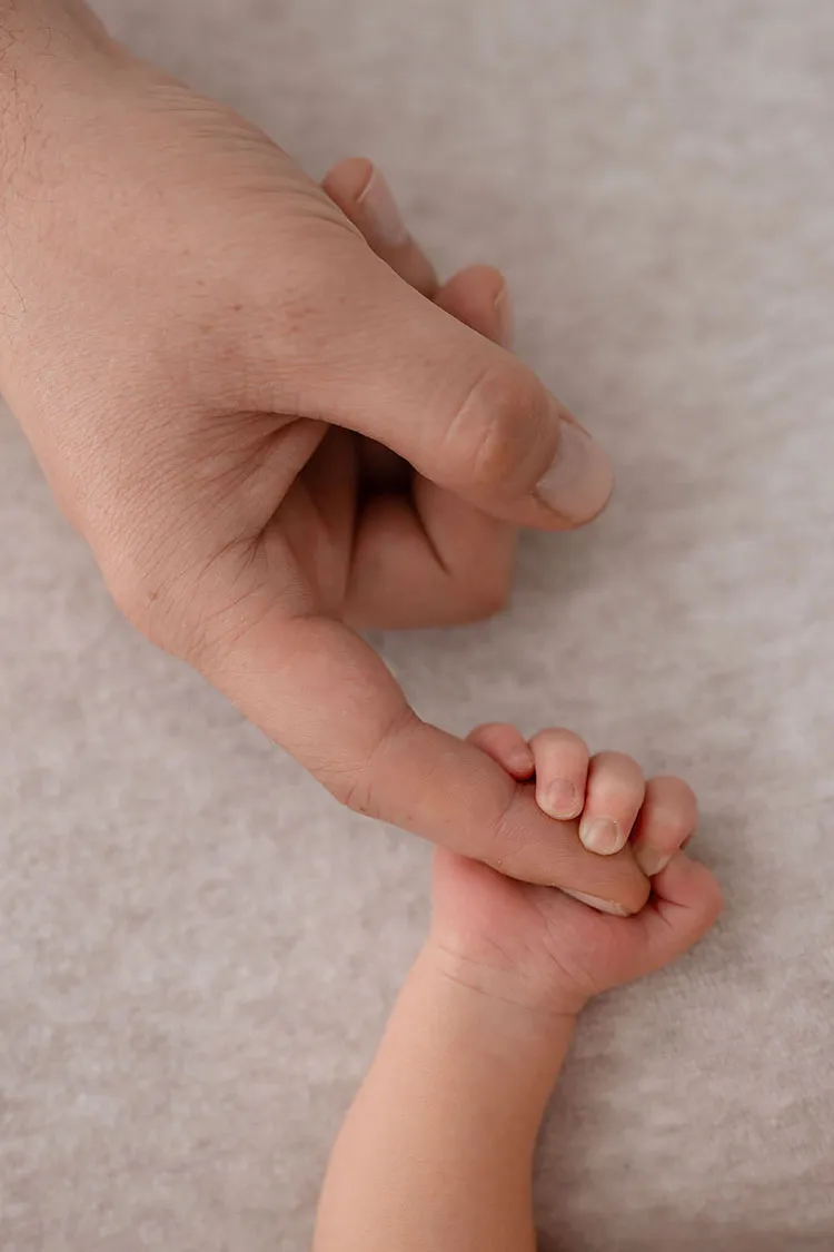 Manina neonato che tiene mano della mamma