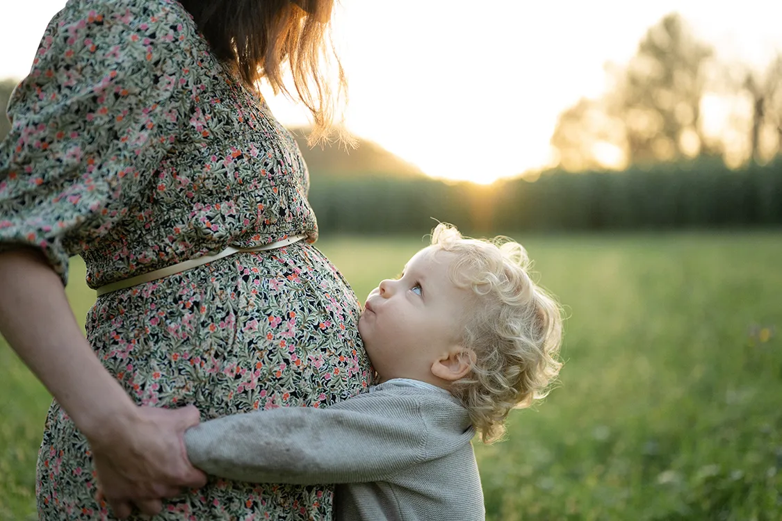Bambino che abbraccia la mamma incinta