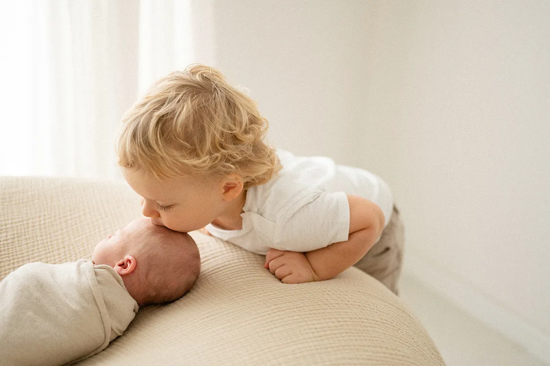 Bambino che bacia il neonato sulla fronte