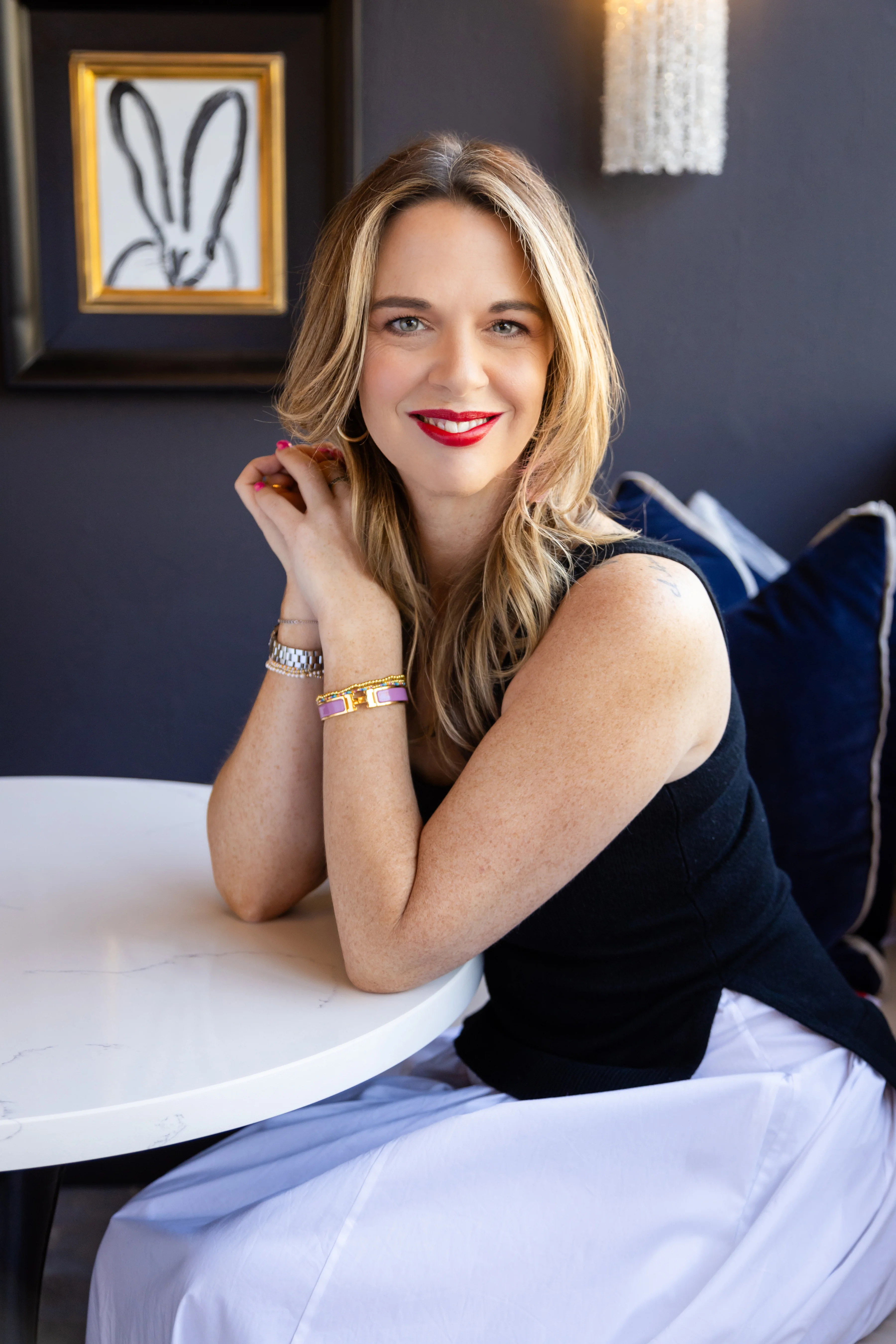 Christine Lord, founder of Luxure Lifestyle, smiling at a white marble table in a navy-walled room