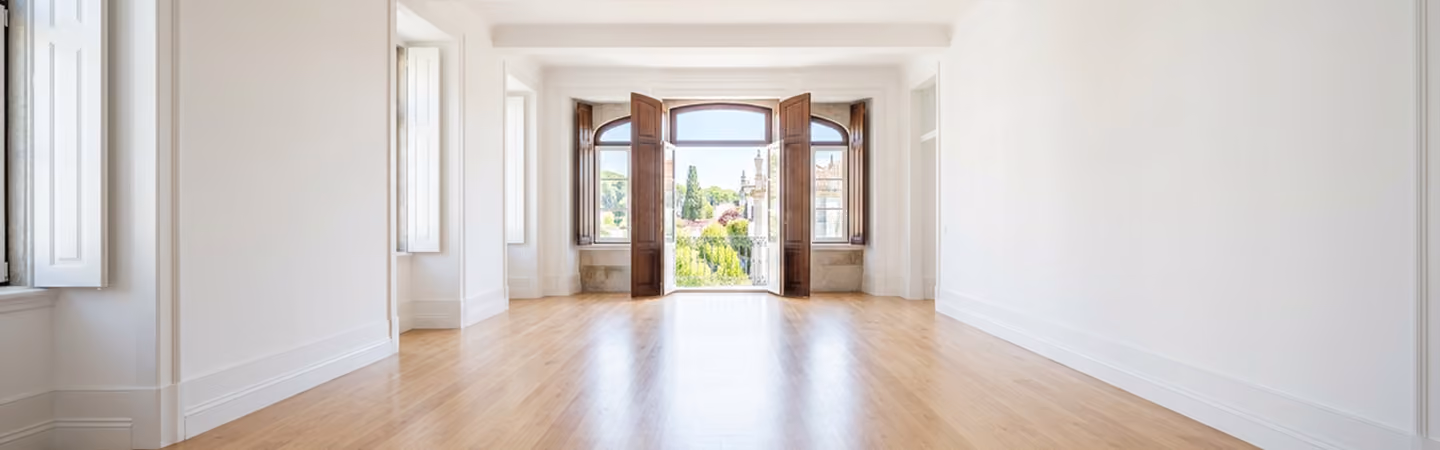 Empty, freshly prepared room with pale oak floors and French doors opening to the terrace