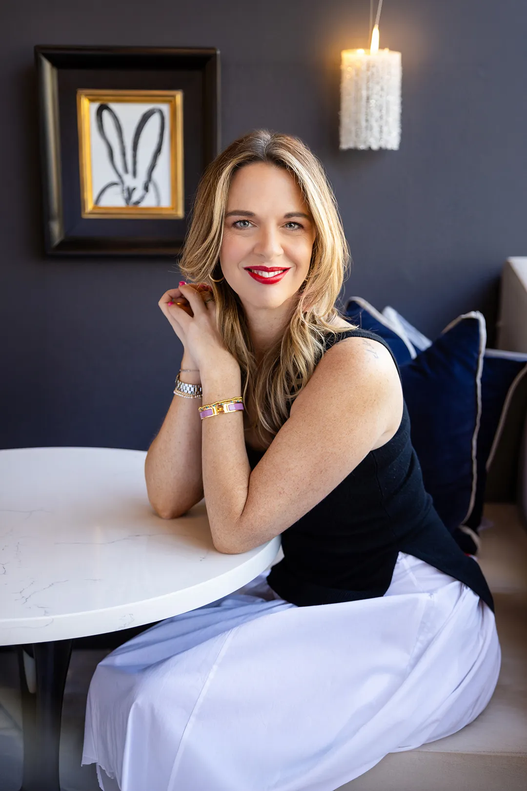 Christine Lord, founder of Luxure Lifestyle, smiling at a white marble table in a navy-walled room