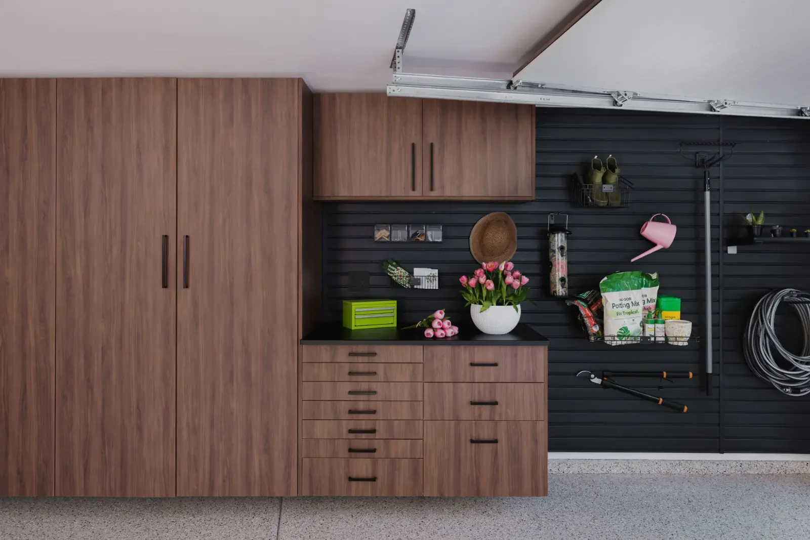 Garage with walnut cabinetry and dark slatwall storage