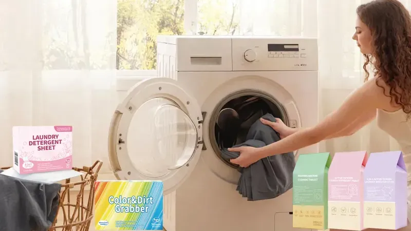 Laundry care products: laundry detergent sheets and washing machine cleaning tablets in retail cartons beside a front-loading washer