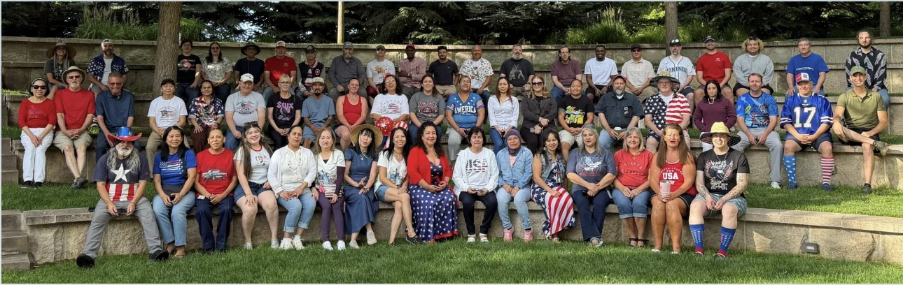 The full company team photographed together outdoors, seated in rows on stone terrace steps