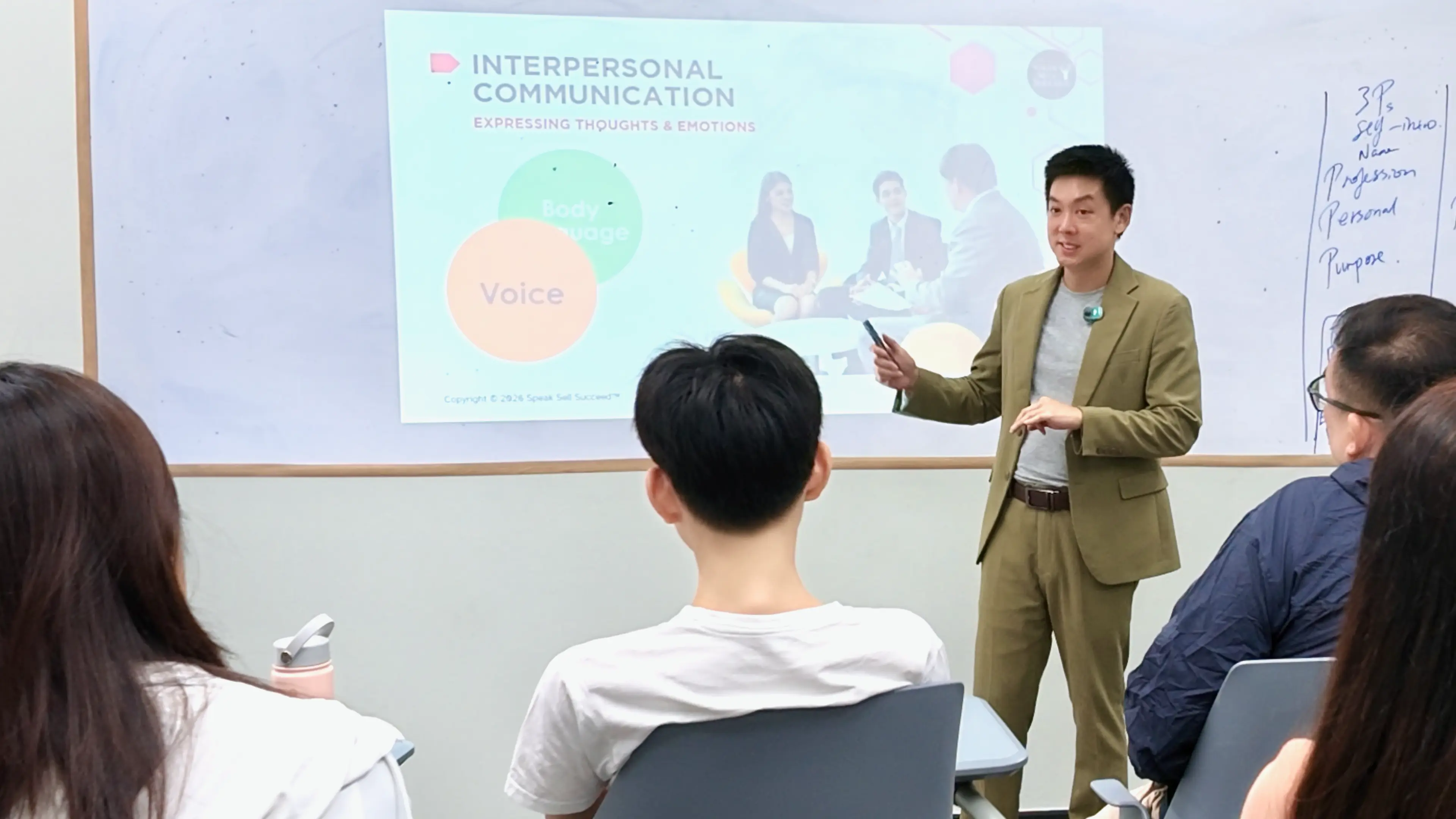 Trainer pointing to slides on interpersonal communication during a public speaking class