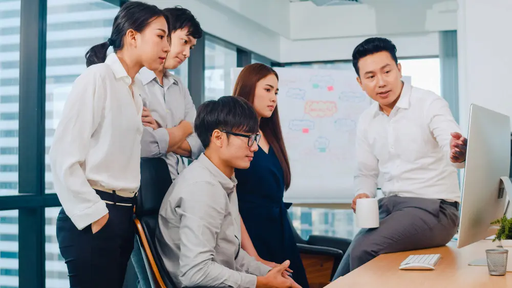 A manager presenting ideas on a screen to his team in an office meeting