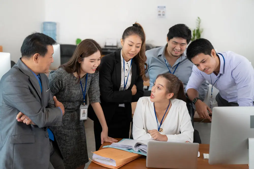 Man explaining an idea to colleagues in a meeting room, with a chart on the screen behind them