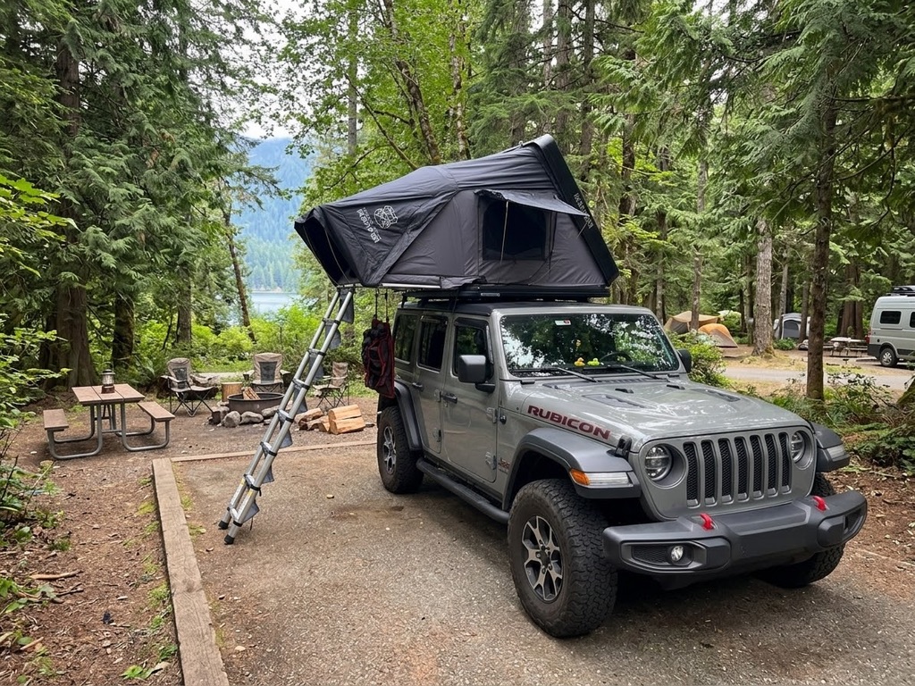 Slate grey Jeep Wrangler Unlimited with iKamper rooftop tent at a Pacific Northwest campsite