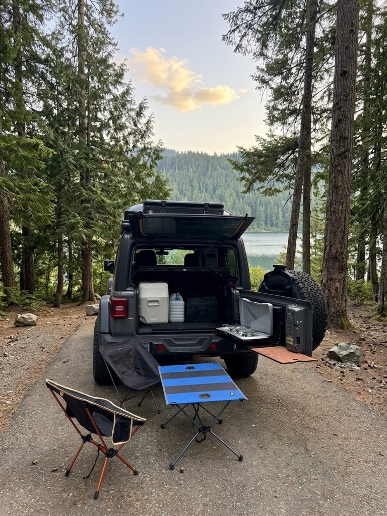 Lakeside tailgate camp kitchen lifestyle setup beside a Jeep Wrangler